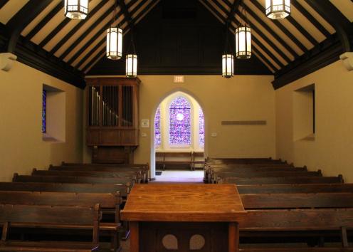 Inside Danforth Chapel behind the podium facing towards the audience with the organ on the left side and stain glass at the end of the aisle